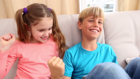 Happy-siblings-looking-at-tablet-pc-on-the-couch