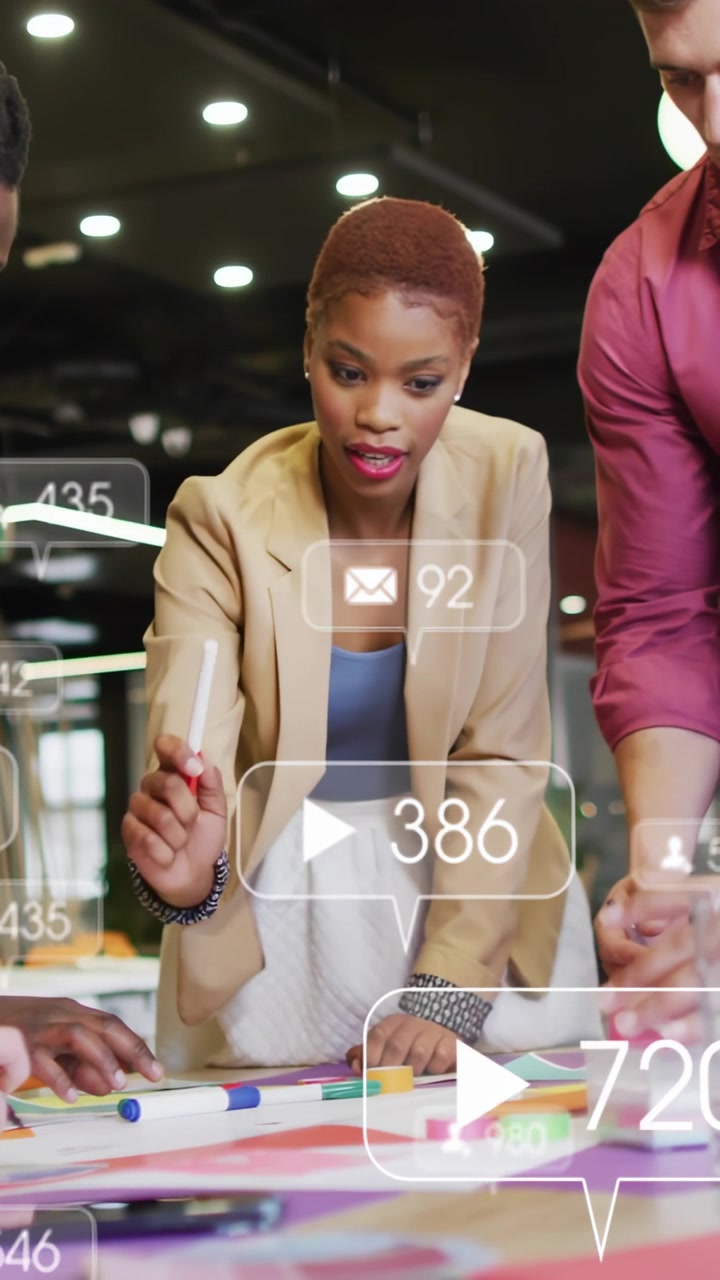 Vertical video: Diverse team lead in blazer pointing pen at table refining layout as stats changing