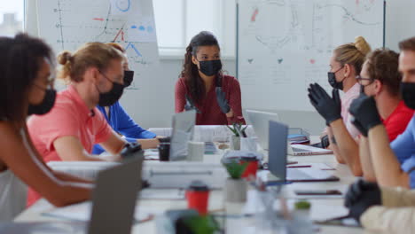 personas enmascaradas hablando en la oficina. colegas multiétnicos trabajando en la nueva normalidad