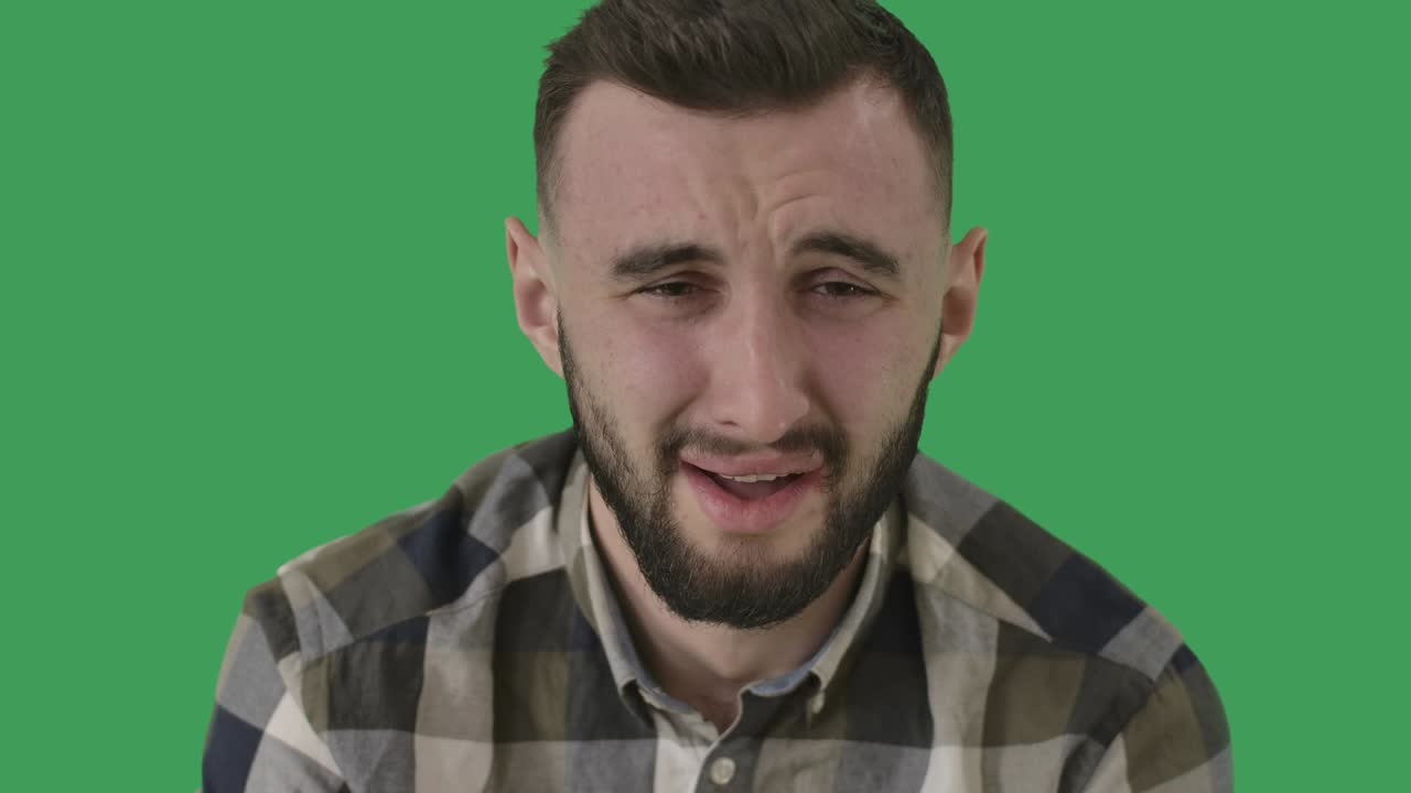 primer plano de un hombre adulto llorando. retrato de un chico guapo caucásico molesto en el fondo de la pantalla verde. chromakey. concepto de tristeza, depresión, alivio emocional. cine 4k prores hq.