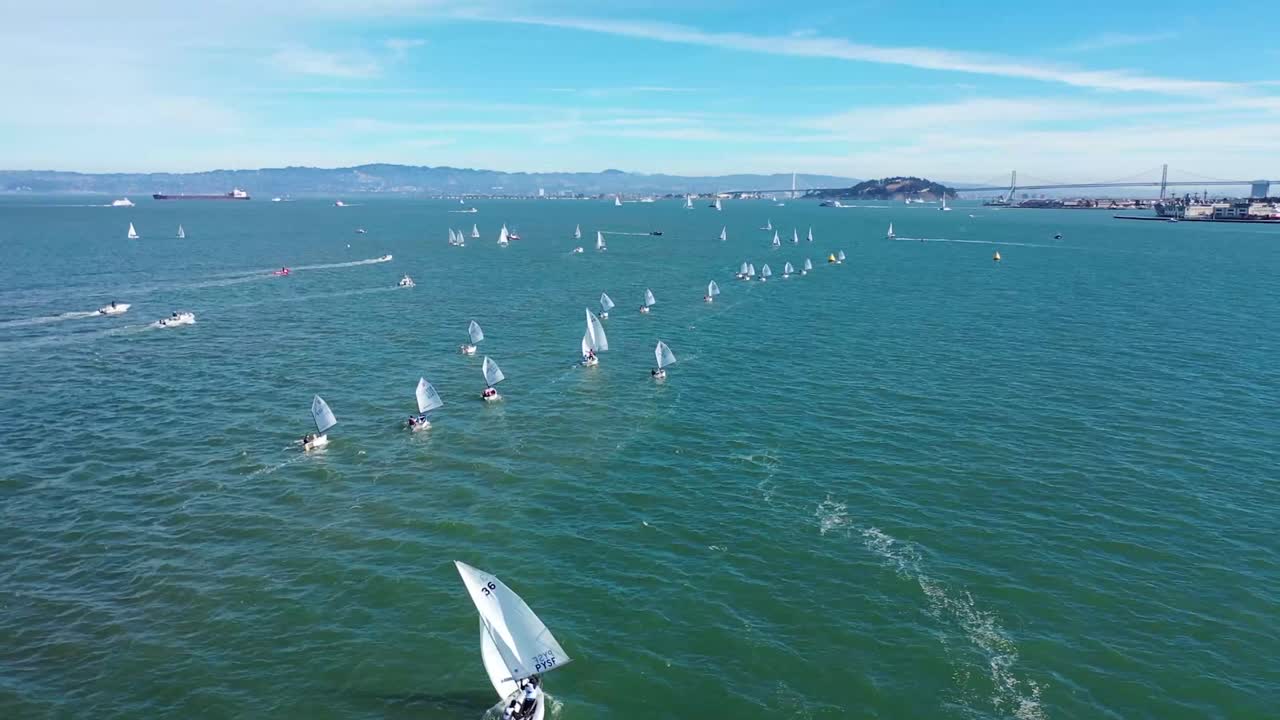 푸른 하늘과 베이 브리지를 배경으로 맑은 날 샌프란시스코 만을 가로질러 작은 범선을 쫓는 드론 샷