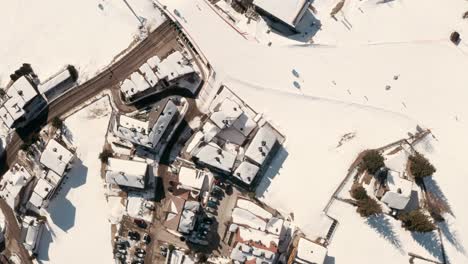 Top-down-drone-shot-of-ski-slope-bridge-over-road-in-a-ski-village-winter