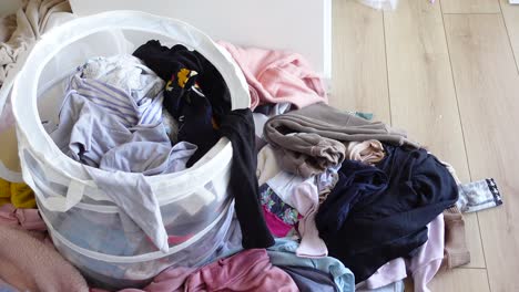 a white laundry basket overflowing with dirty clothes