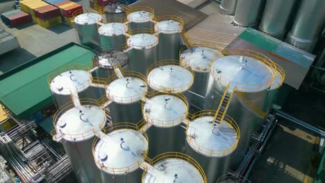 drone orbit view of close up palm kernel oil tanks in oil refinery plant, malaysia