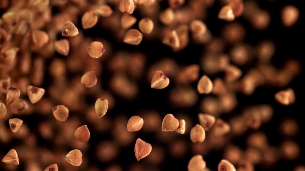 Buckwheat Grains Falling in Super Slow Motion Against a Black Background
