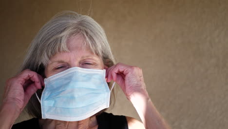 an aging old stick woman smiling with hope while putting on a medical patient mask before surgery