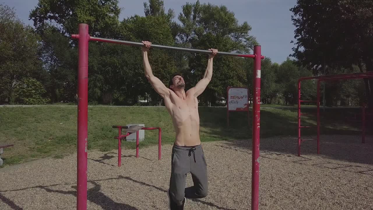 persona masculina haciendo flexiones en la barra en el parque