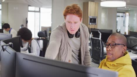 diverse male business colleagues pointing at computer and discussing in office