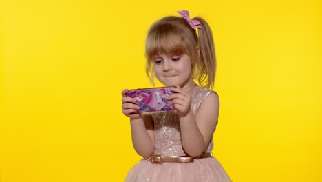 niña usando un teléfono inteligente. niño enviando mensajes de texto en el teléfono electrónico. niño jugando juegos en el teléfono móvil en el estudio