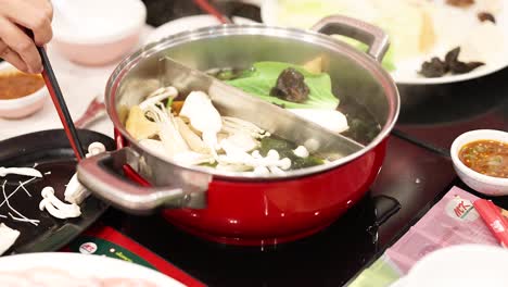 preparing hotpot with vegetables and broth