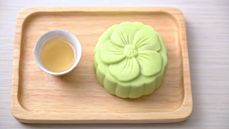 Chinese-moon-cake-green-tea-flavour-with-tea-on-wood-plate