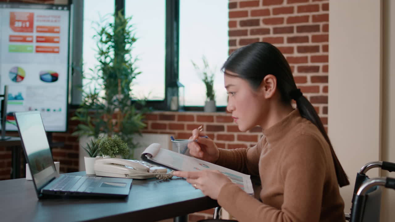 Worker in wheelchair analyzing business charts on documents