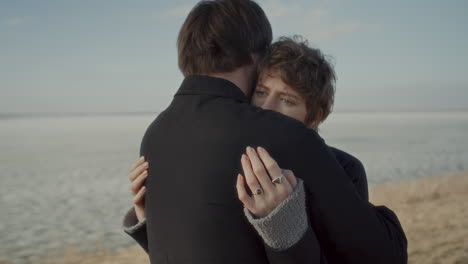 young woman gently embracing boyfriend on frozen lake shore