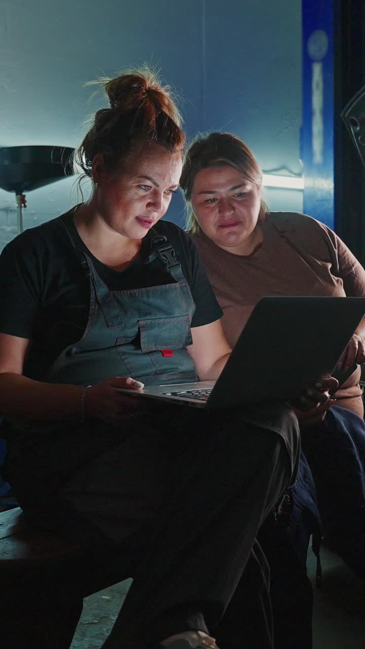 Two Women in a Repair Shop Working on a Laptop