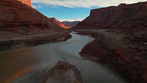 bright river winds below jagged cliffs in rugged desert canyon at golden hour before sunset, moab utah usa