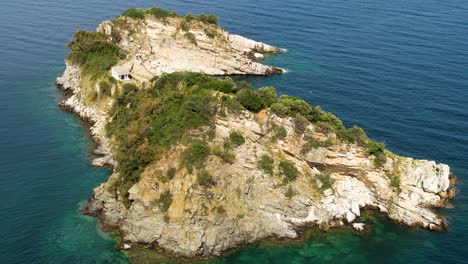 aerial view over gramvousa island with the camera slowly tilting down to reveal a white church surrounded by majestic cliffs and lush vegetation, thassos island, greece, europe