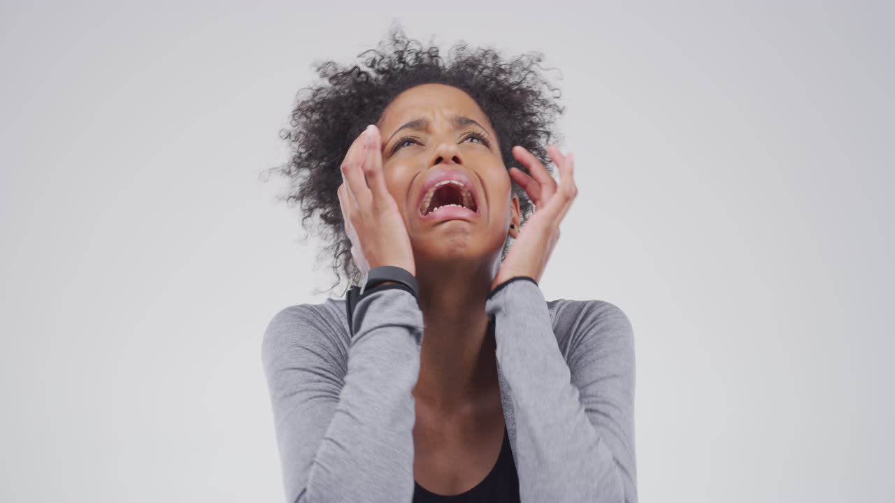 una mujer joven atractiva llorando contra un gris