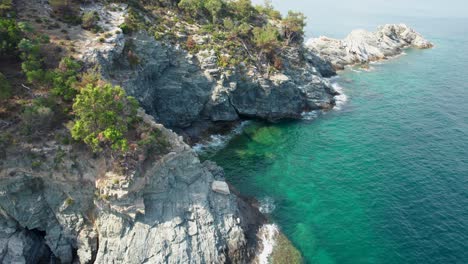 Top-Down-View-Over-A-Seaside-Cliff-With-Small-Isolated-Beaches,-Crystal-Clear-Water-And-Green-Vegetation-,-Thassos-Island,-Greece,-Europe