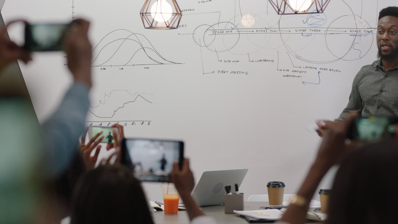 아프리카계 미국인 사업가 들 이 성공 한 사업가 들 을 만나고 경영 그룹 동료 들 에게 기업 의 아이디어 를 공유 하고 스마트폰 을 사용 하고 비디오 를 찍고 회의실 에서 커뮤니케이션 프레젠테이션 을 즐기고 있다