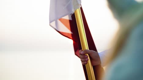 un caballero que sostiene la bandera de qatar a caballo cerca del mar en el desierto de qatar-2