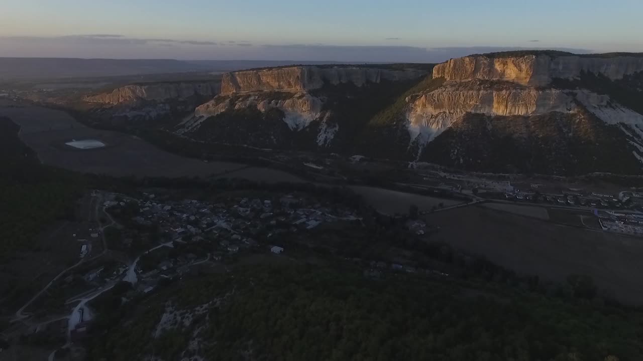 해가 지는 동안 산과 마을이 있는 계곡의 공중 풍경