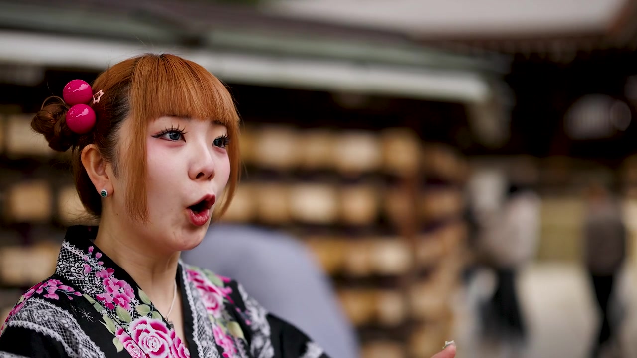 A young woman in traditional kimono talks near wooden prayer plaques at a Tokyo shrine.