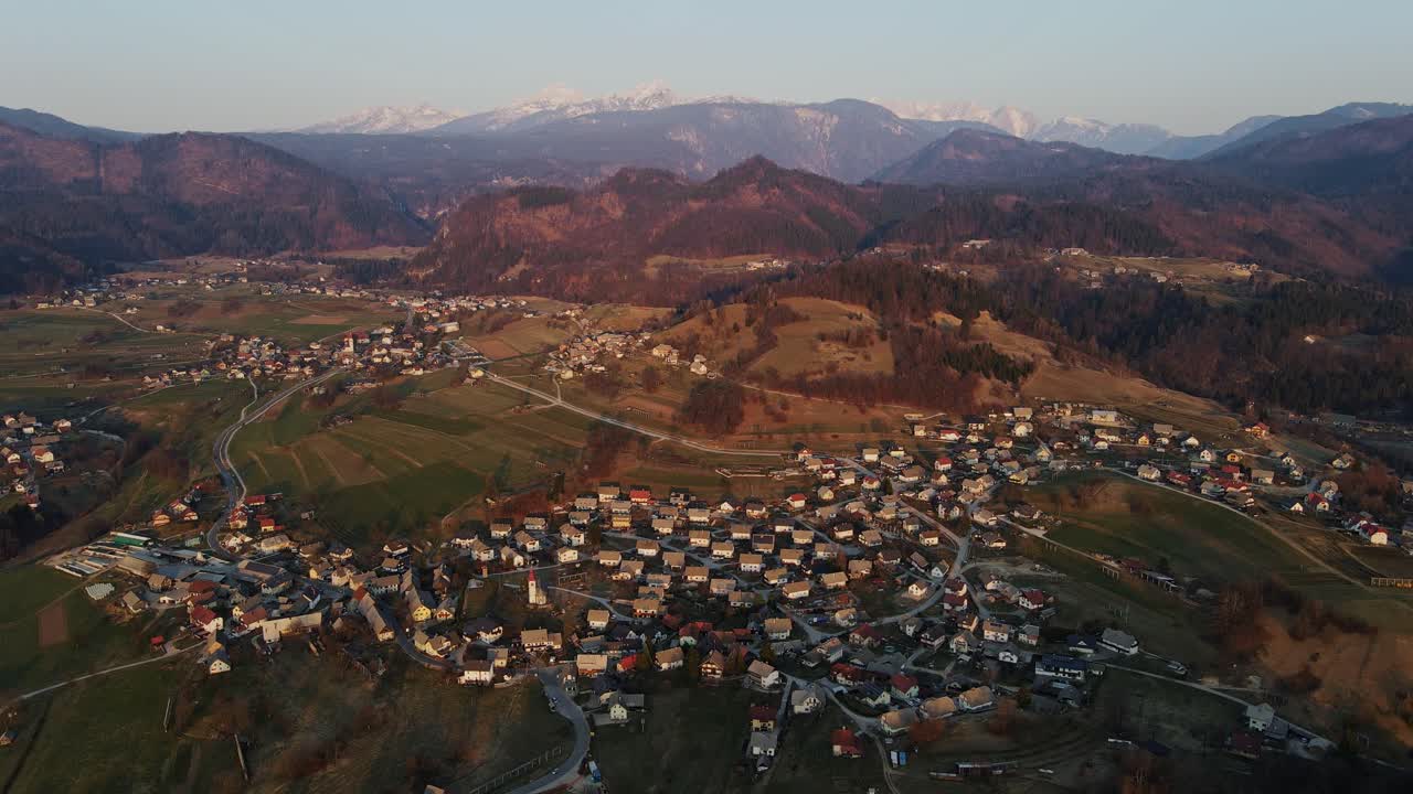 Aerial view of Spodnje Gorje in morning light - village and snow-capped peaks