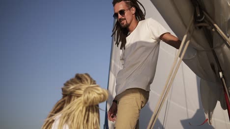 estilo de vida saludable al aire libre navegando en un yate de lujo con una joven pareja elegante disfrutando de la relajación y la libertad. pareja joven caucásica con rastas. vista de ángulo bajo