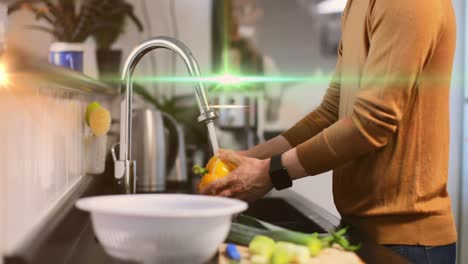 Animation-of-light-moving-over-midsection-of-caucasian-man-washing-vegetables-in-kitchen