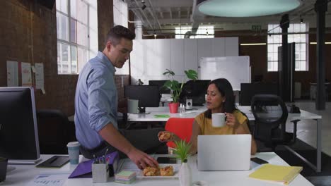 Diverse-male-and-female-business-colleagues-eating-pastries-drinking-coffee-and-smiling