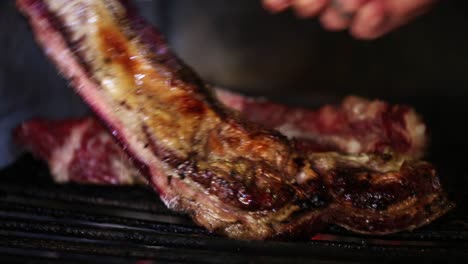 close-up of a man cooking an argentinian asado on a grill