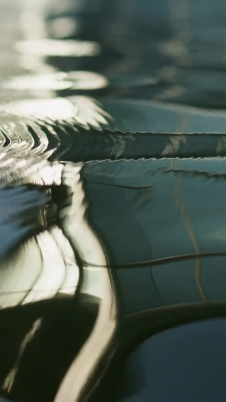 Vertical video: Rippling calm water at closeup following upper-left ripple bending grid reflections