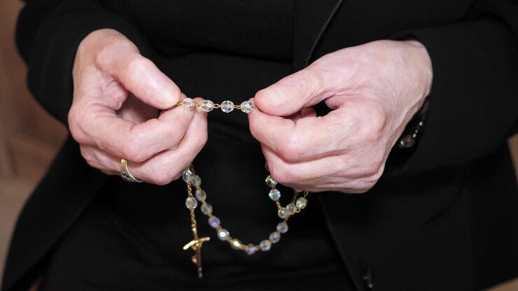 Anziana donna cristiana che prega con il rosario