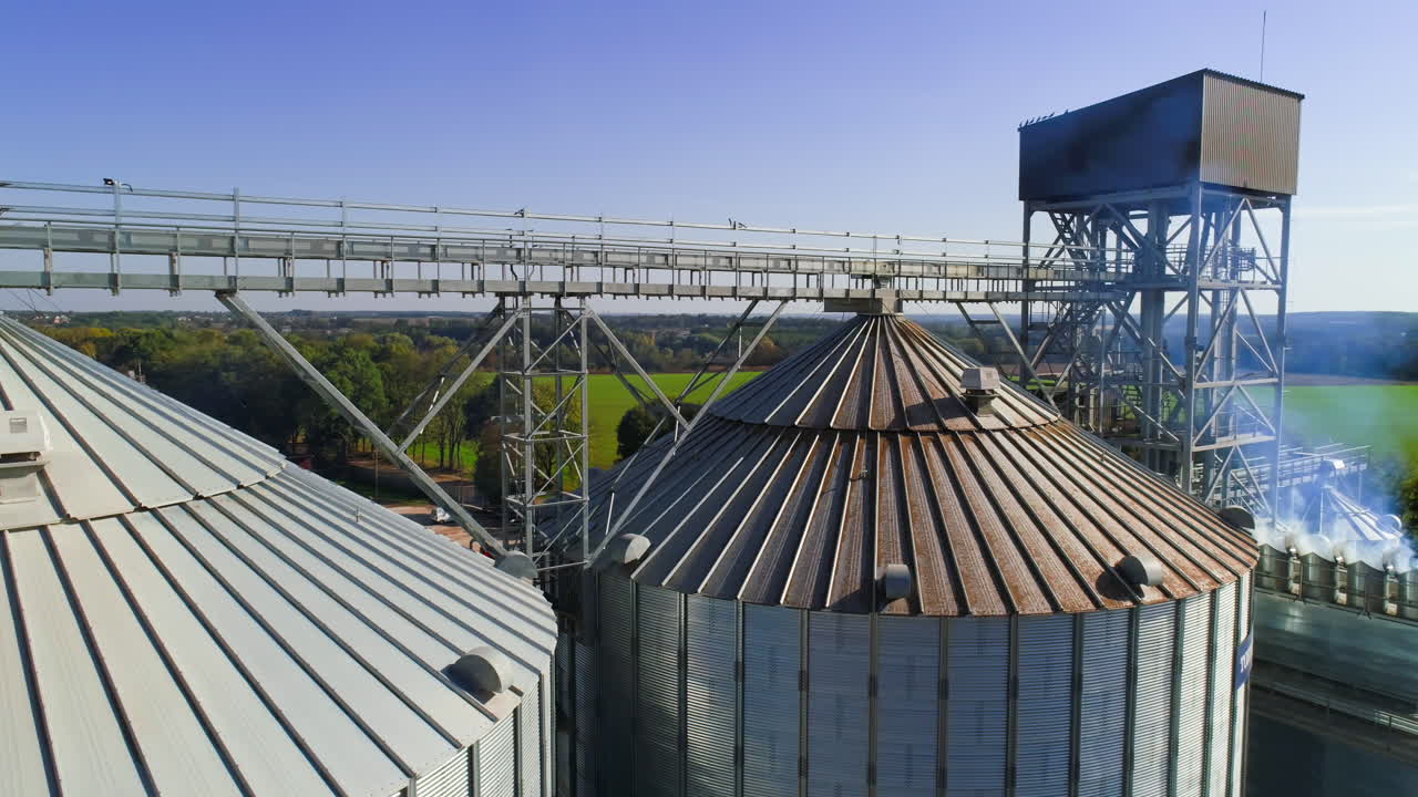 Large steel towers for storing crops. Aerial view of grain terminal with closed warehouse and silos