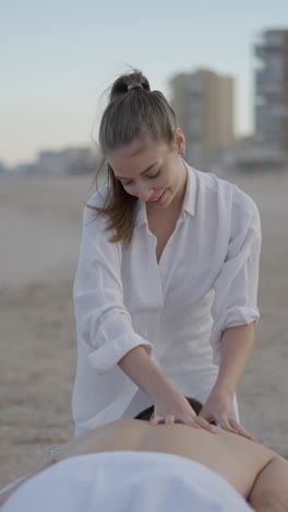 woman giving a back massage on a sandy beach