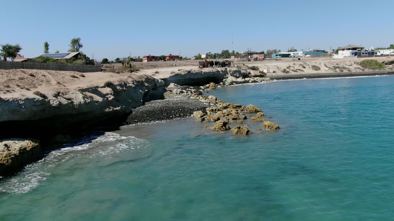 Aerial view Moving forward shot, Scenic view of Rocky shoreline of San Juanico, California Sur, Mexico, restaurant on the edge of the cliff in the background
