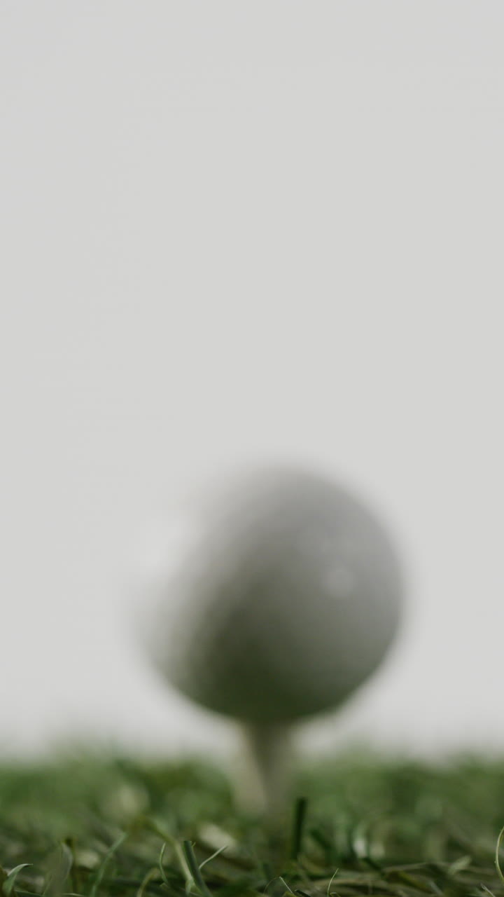 Vertical viedo of golf ball on grass and white background, copy space, slow motion