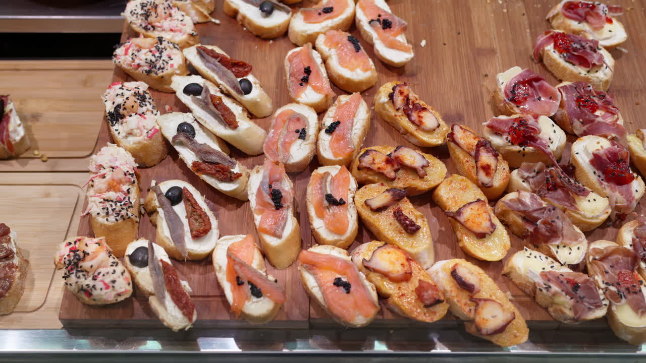Close up of tapas with salmon, octopus, and ham on baguette slices in a bar in Valencia, Spain
