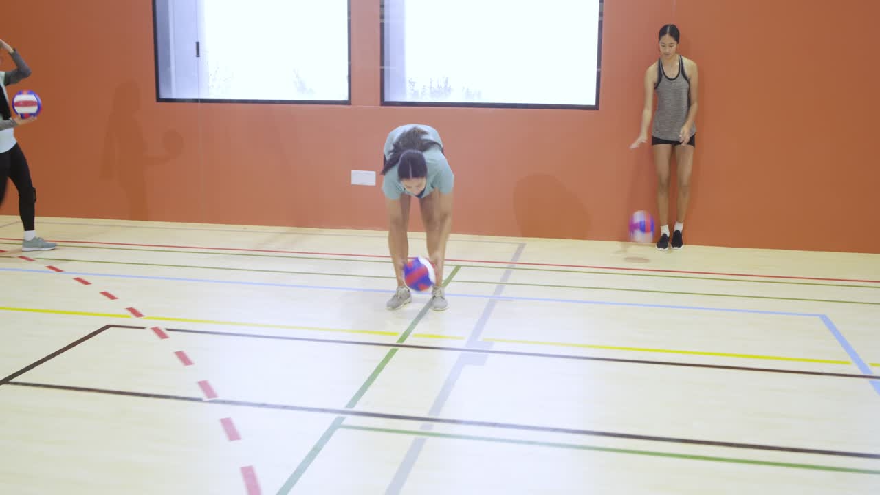 Donne di diverse etnie che si allenano in palestra, una cammina dalla parete destra con una palla da pallavolo, con spazio per il testo