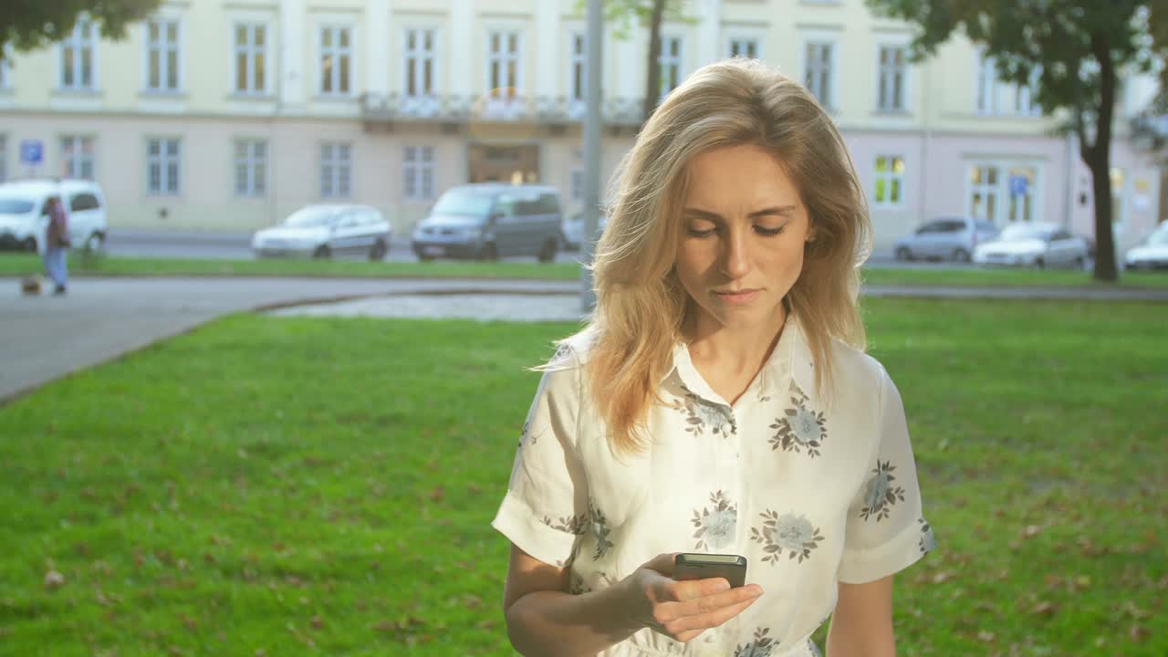 привлекательная девушка в шляпе идет по улице в старом городе и разговаривает по телефону на рассвете