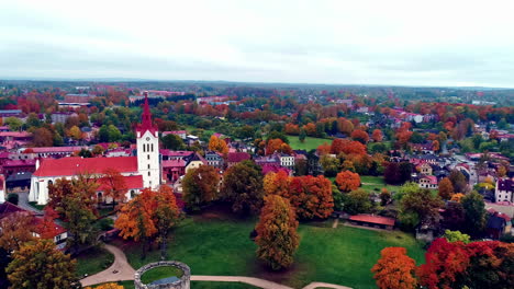 vista aérea hacia atrás de un castillo medieval- castillo de cēsis en letonia rodeado de árboles otoñales en un día nublado