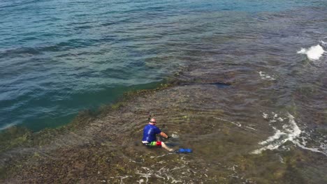 hombre en un arrecife de coral poco profundo listo para bucear en la actividad de buceo submarino en vacaciones