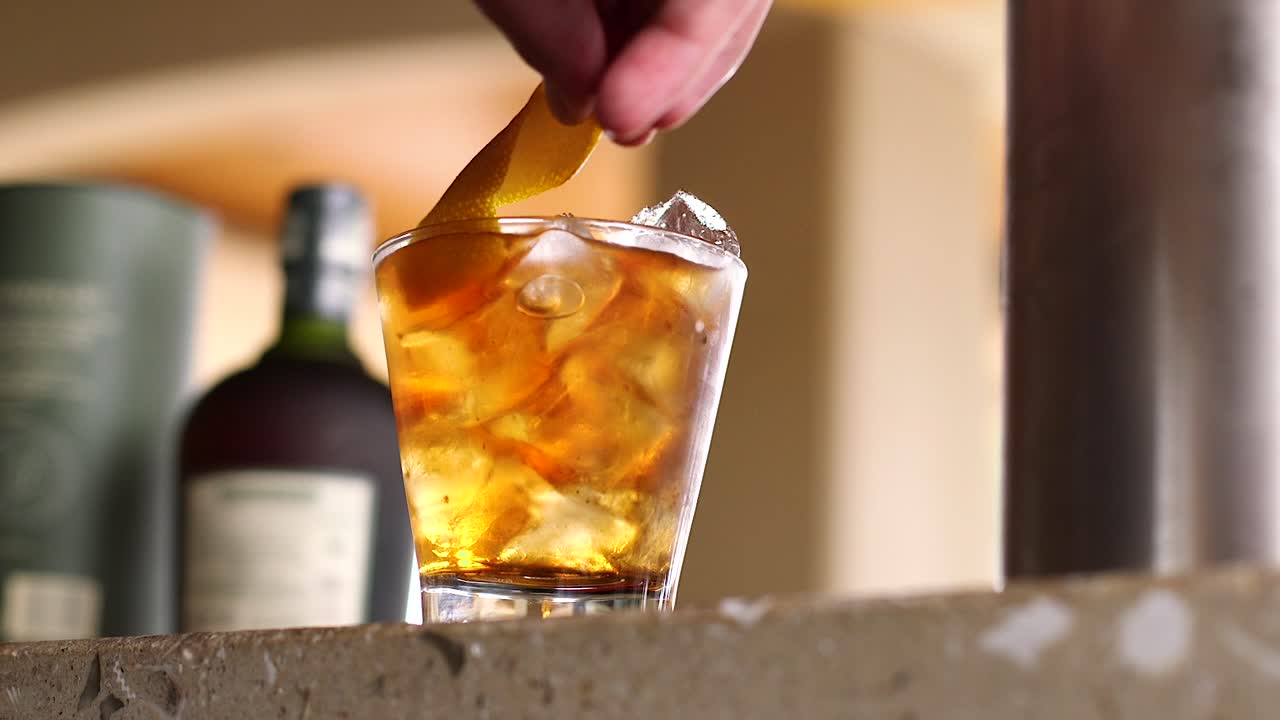 camarero adornando una bebida alcohólica con un toque de naranja en un bar en el caribe