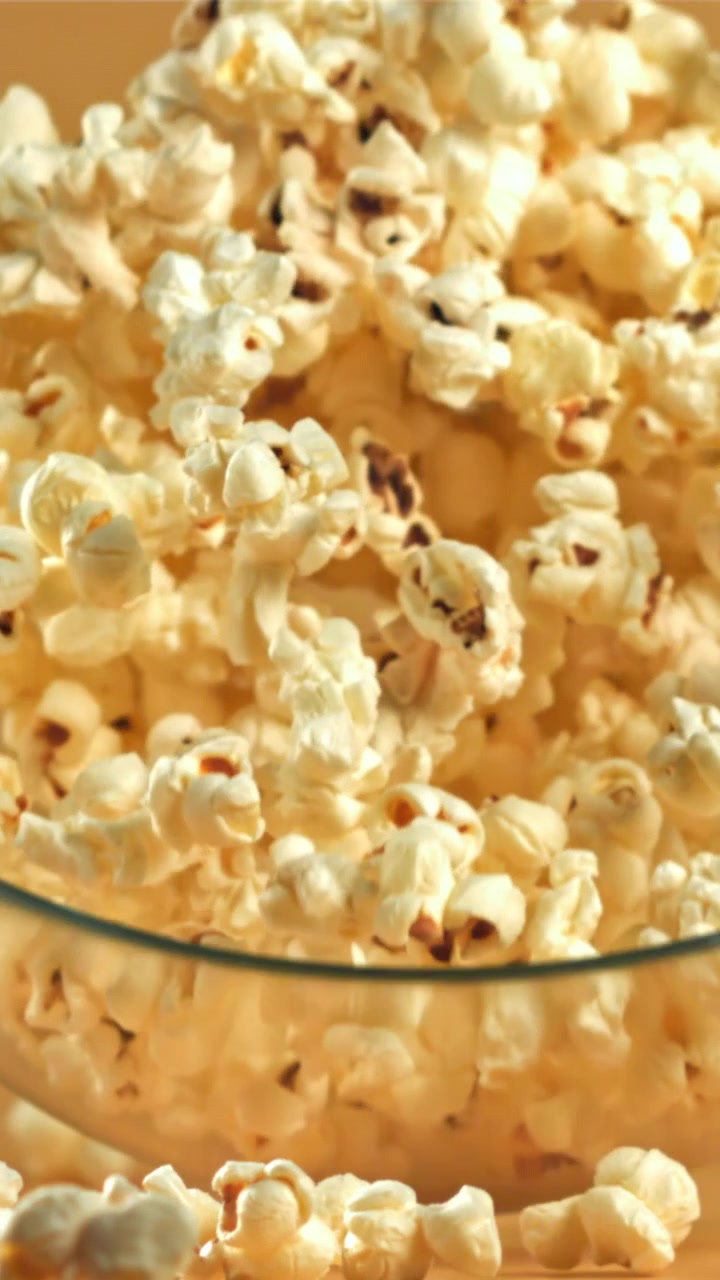 Popcorn che si riversano al rallentatore in una ciotola di vetro e traboccano
