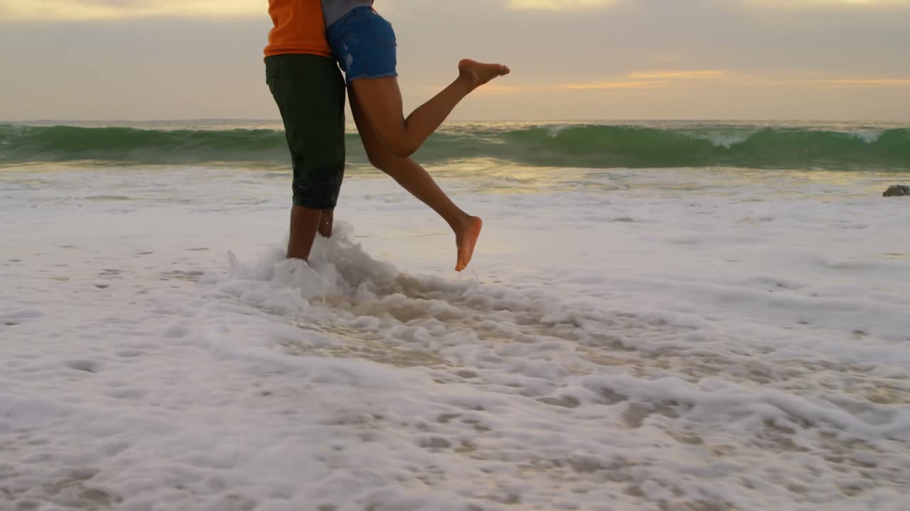 sección baja de una pareja afroamericana abrazándose en la playa 4k