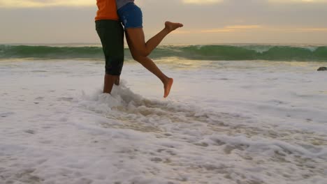 Low-section-of-African-american-couple-embracing-each-other-on-the-beach-4k