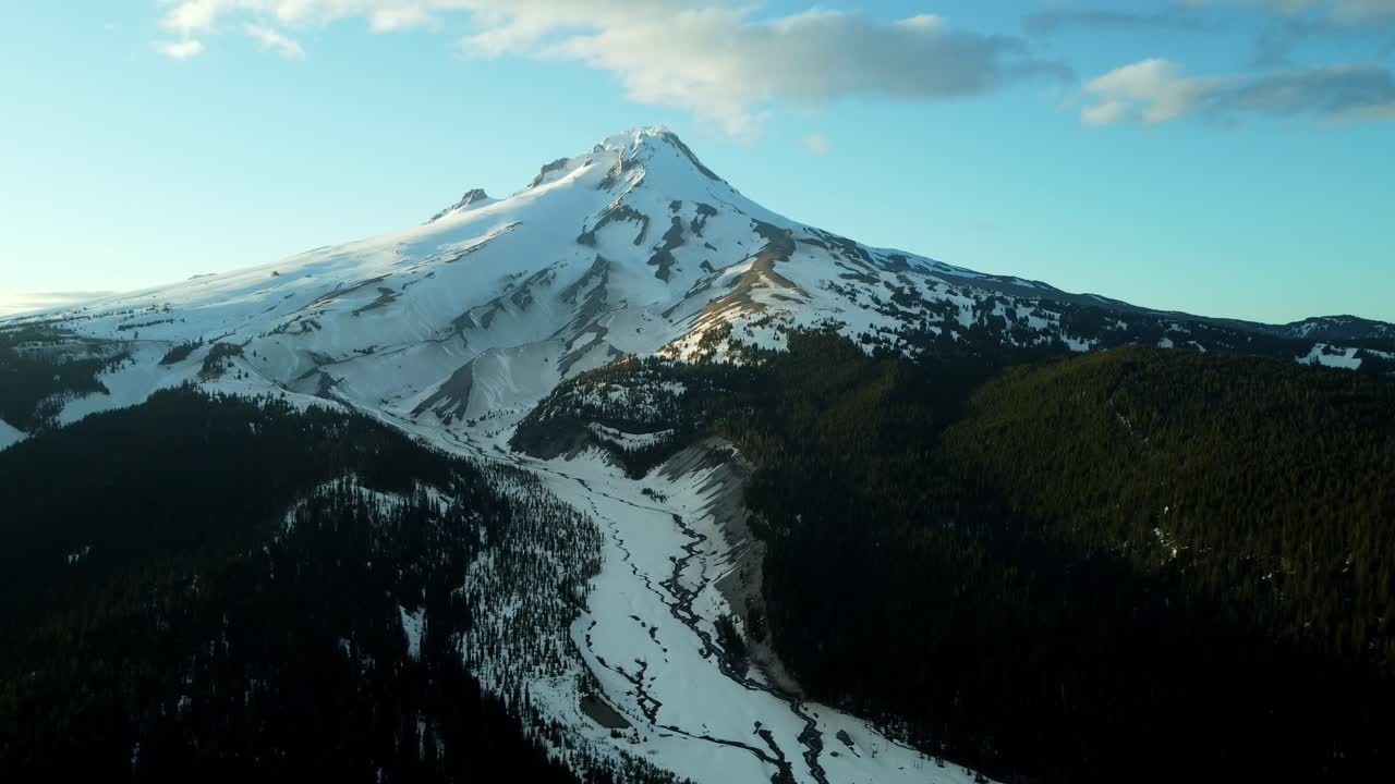 US, Oregon, Mt Hood, White River, 2025-04-22 - Drone view of Mt Hood at sunset over the White River in spring, with snow still covering the mountain and creek and trees