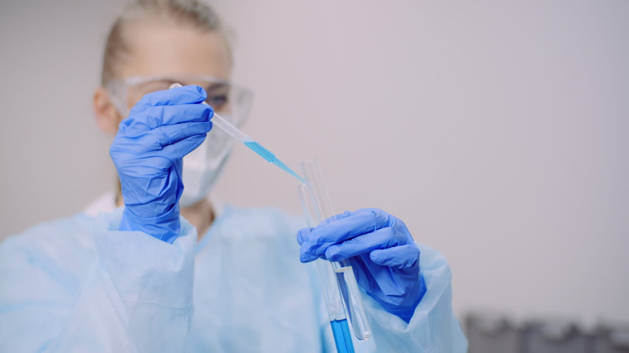 врач осторожно капает лекарство из пипетки в стеклянные пробирки для анализа днк в лаборатории