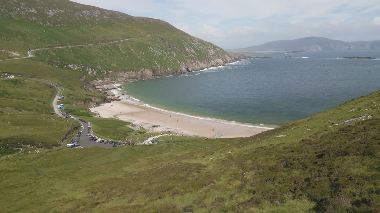 imágenes de drones volando sobre la bahía de keem, revelando sus aguas turquesas, playa de arena y acantilados circundantes