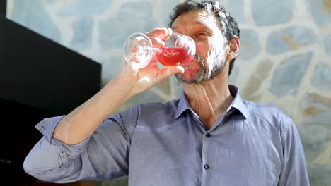 man in a blue shirt tastes wine and is startled by the flavor. slow-motion. drinking red wine sunny day outdoors